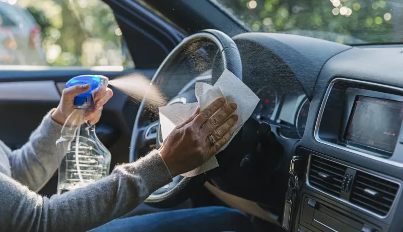 Une femme nettoie sa voiture avec un chiffon