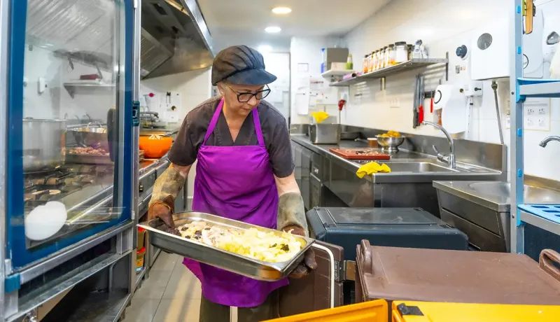     Une femme préparant des aliments dans une cuisine moderne, entourée d'ustensiles et d'ingrédients.