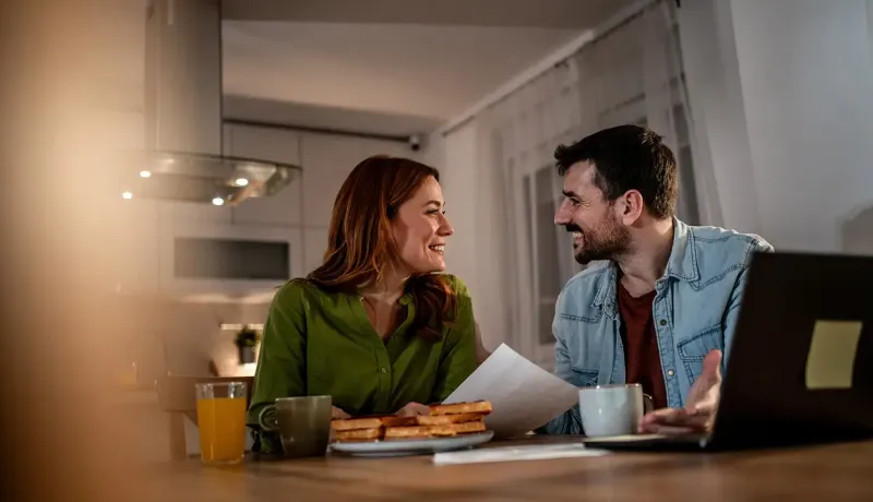 Un homme et une femme assis à une table, utilisant un ordinateur portable.