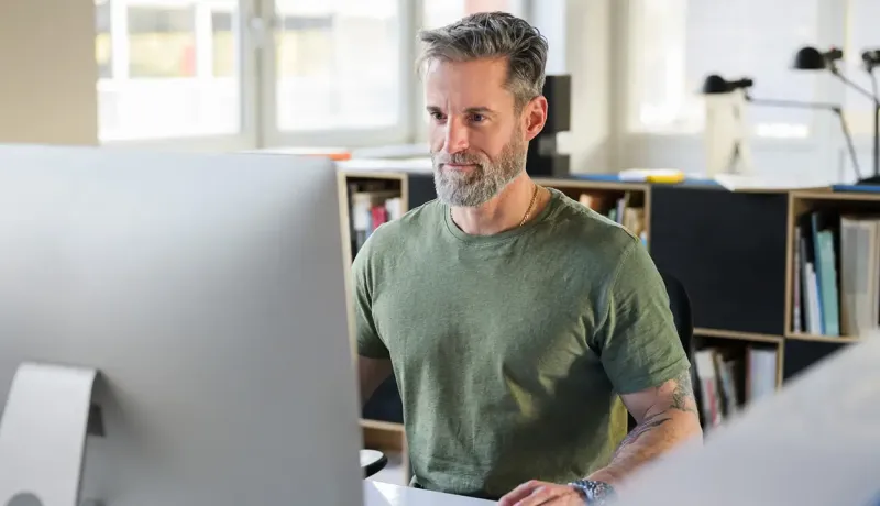 Un homme assis à un bureau devant un ordinateur, concentré sur son travail.