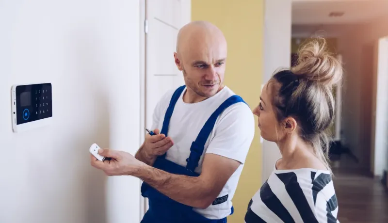 Installation de système de sécurité : l'expert montre les fonctionnalités du clavier et du porte-clés à la cliente.