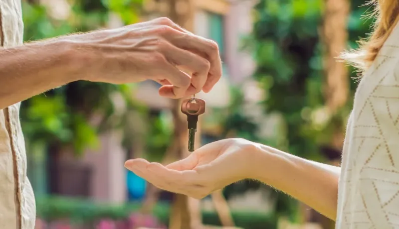 Un jeu de clés est passé d'une main à une autre en gros plan, symbolisant l'achat ou la location d'un bien.