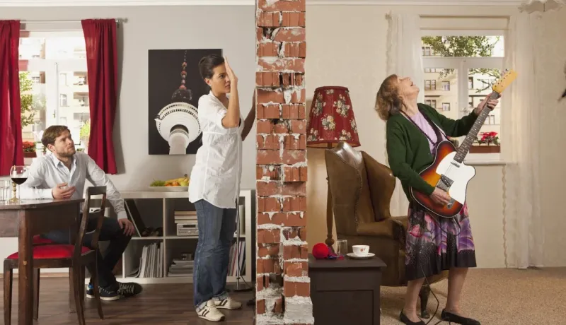 Le concept de voisins bruyants est illustré par un mur brisé séparant un couple d'une femme jouant de la guitare.