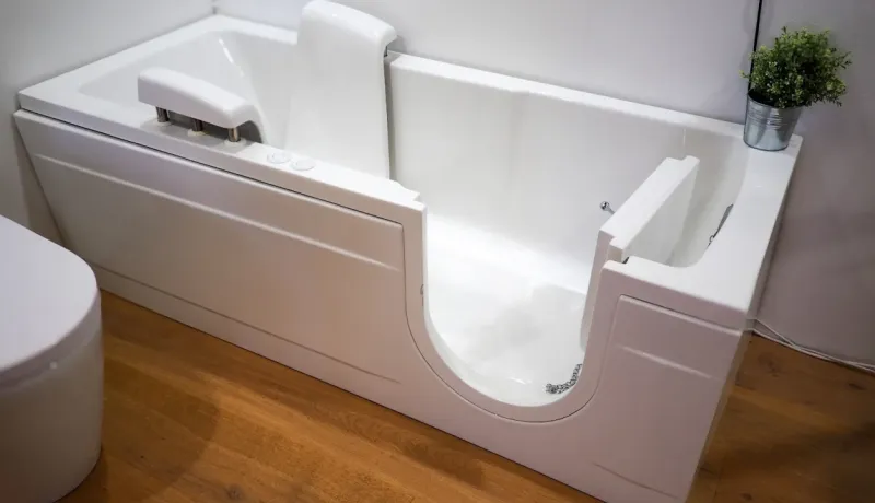 Une baignoire de plain-pied blanche et moderne, conçue pour un accès facile et sécuritaire, dans une salle de bain en bois.
