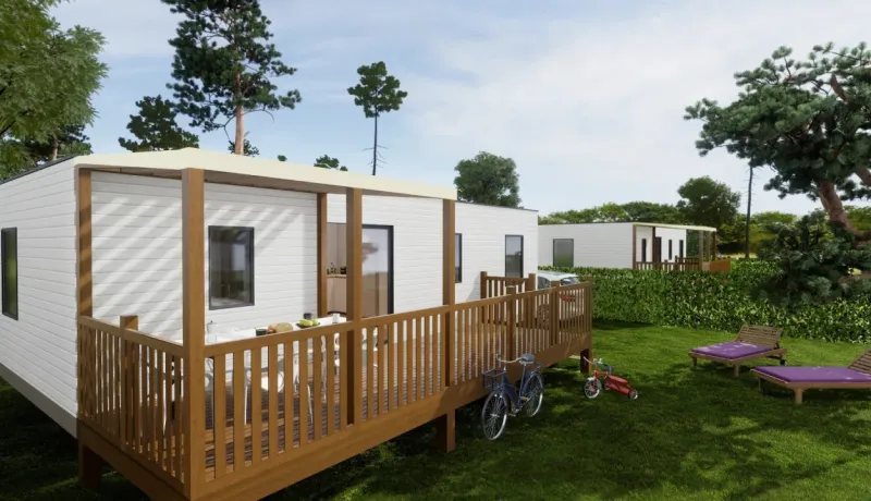 Maisons mobiles modernes avec terrasse en bois, pelouse verte et vélos, dans un cadre de vacances ou de camping.