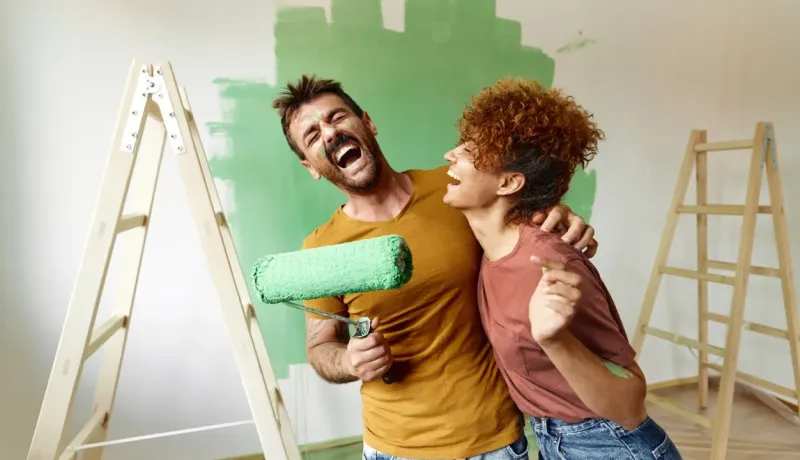 Un couple joyeux et éclaboussé de peinture verte fait une pause amusante pendant qu'ils rénovent leur intérieur.