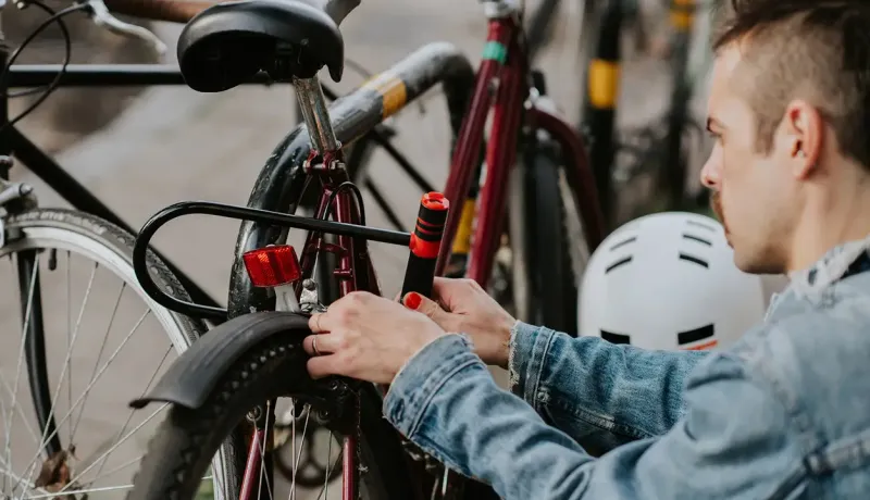 Un homme répare un vélo tout en portant un casque de sécurité.