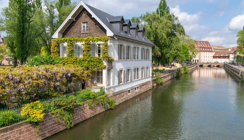 Maison ancienne fleurie située au bord d'un canal urbain.