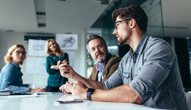 Quatre professionnels en réunion dans un bureau.