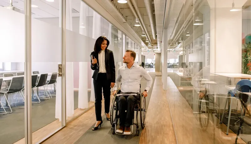 Personne en fauteuil roulant dans un couloir d'entreprise.