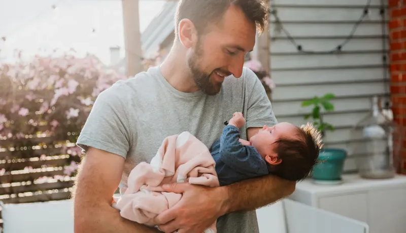 Père tenant son bébé dans ses bras.