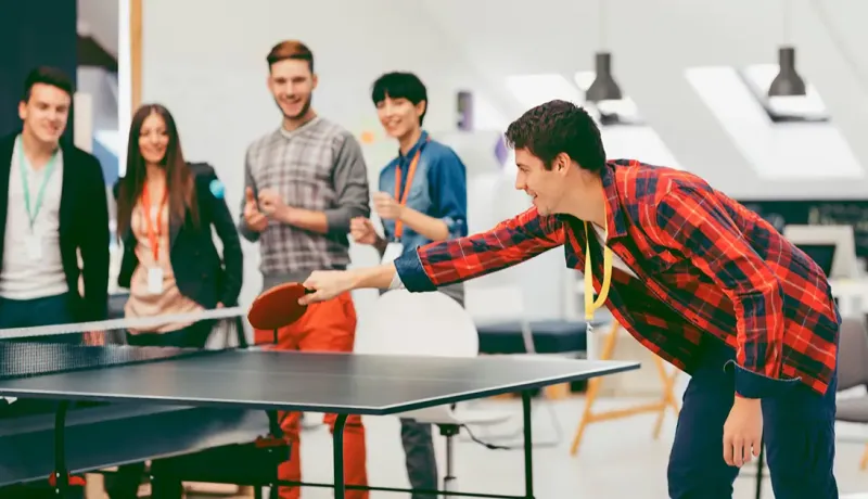 Un groupe de salariés joue au tennis de table, dans le cadre d'un atelier collaboratif en équipe.