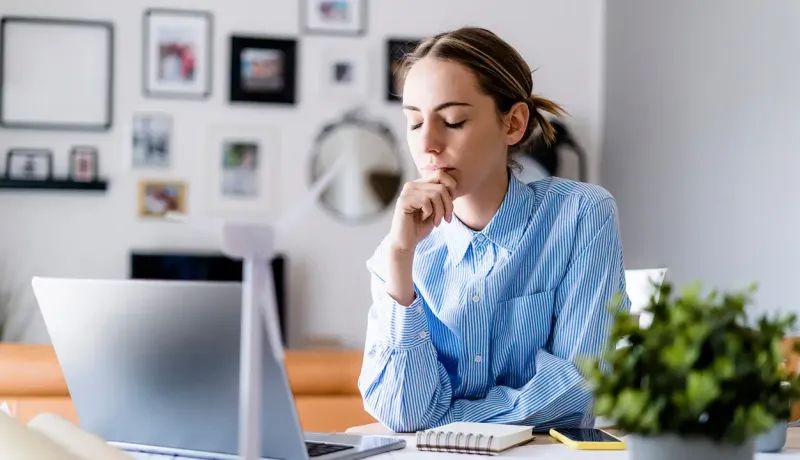 Une professionnelle travaillant à domicile sur son ordinateur prend une pause en fermant les yeux.