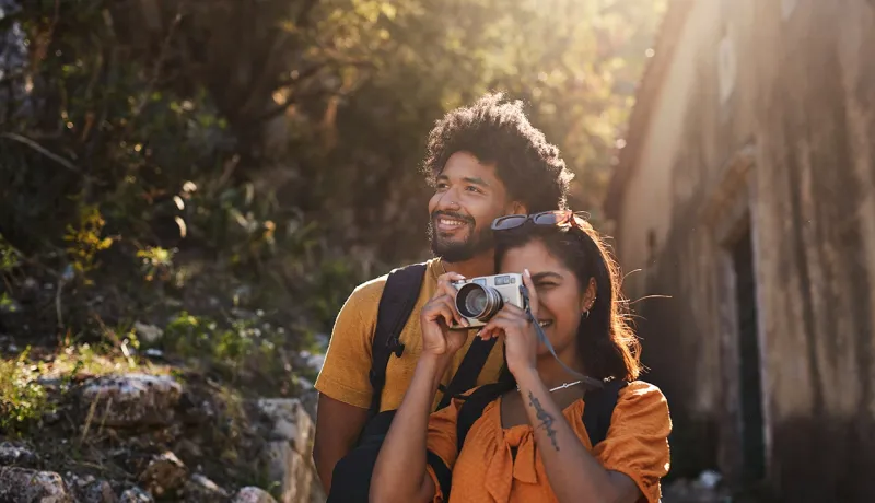 Un couple souriant prend une photo avec un appareil photo.