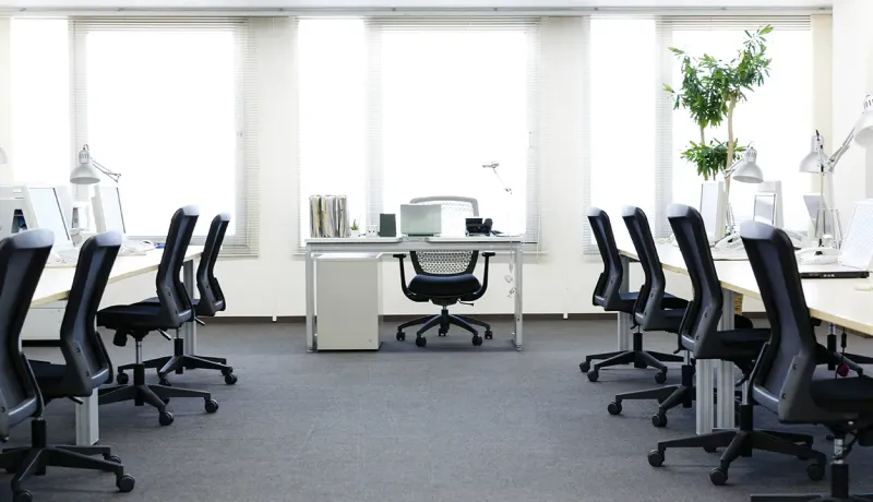 Bureau moderne avec un fond blanc et des chaises noires, créant une ambiance professionnelle et épurée.