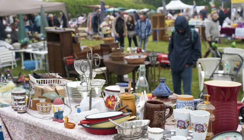 Une table chargée d'objets variés dans un marché aux puces, incluant des vêtements, des livres et des antiquités.