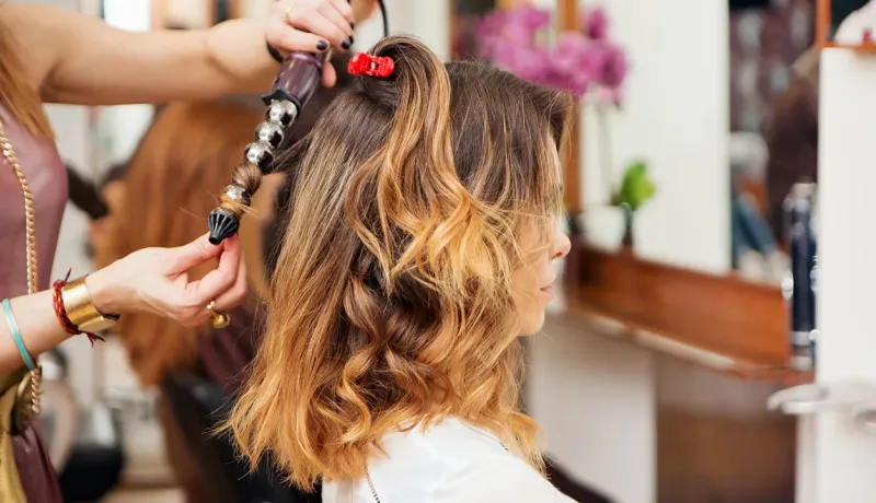 Coiffeuse réalisant une coupe de cheveux en salon.