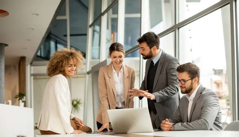 Équipe de salariés en train de parler dans un bureau devant un ordinateur.