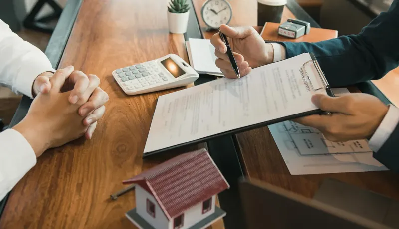 Agent immobilier présentant un contrat à signer.