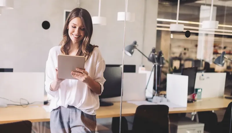 Femme travaillant sur une tablette dans un bureau moderne.