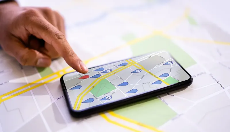 Main pointant du doigts des puces de géolocalisation sur un smartphone.