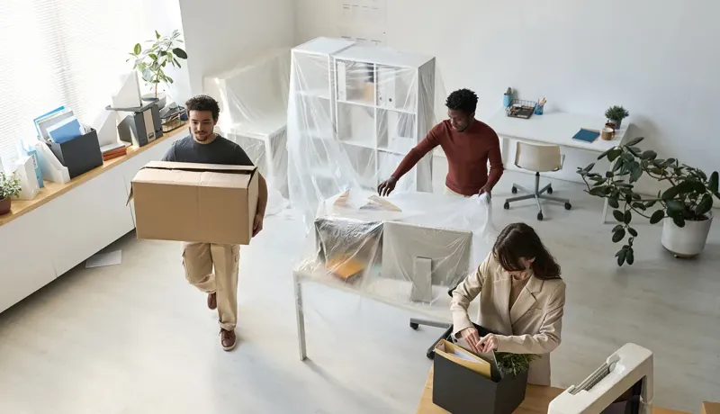 Personnes transportant des cartons de déménagement dans un bureau.