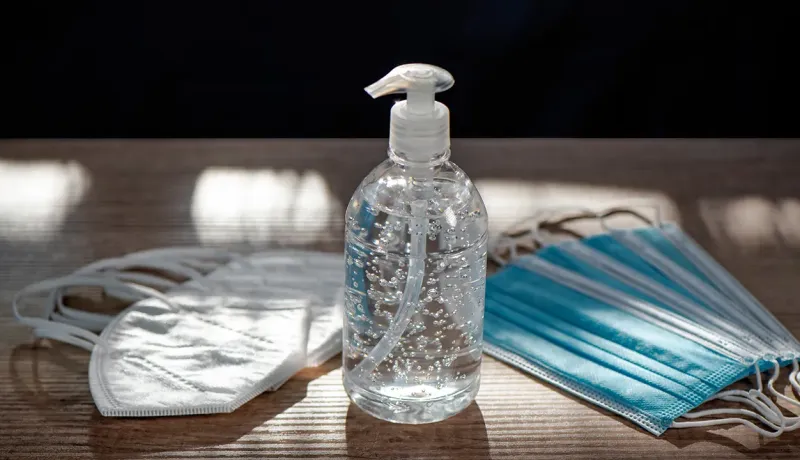 Un gel hydroalcoolique avec deux masques sur une table