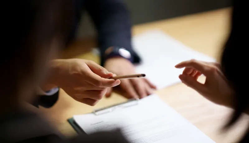 Une personne écrit avec un stylo sur une feuille de papier.