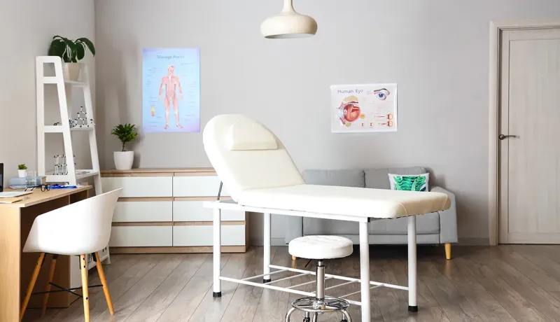 Bureau médical avec une chaise blanche et un bureau, créant un environnement professionnel et accueillant