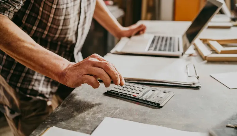Personne utilisant une calculatrice et un ordinateur pour gérer une opération financière