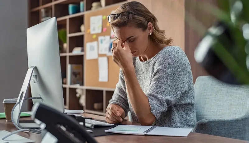 Femme se tenant la tête devant un ordinateur