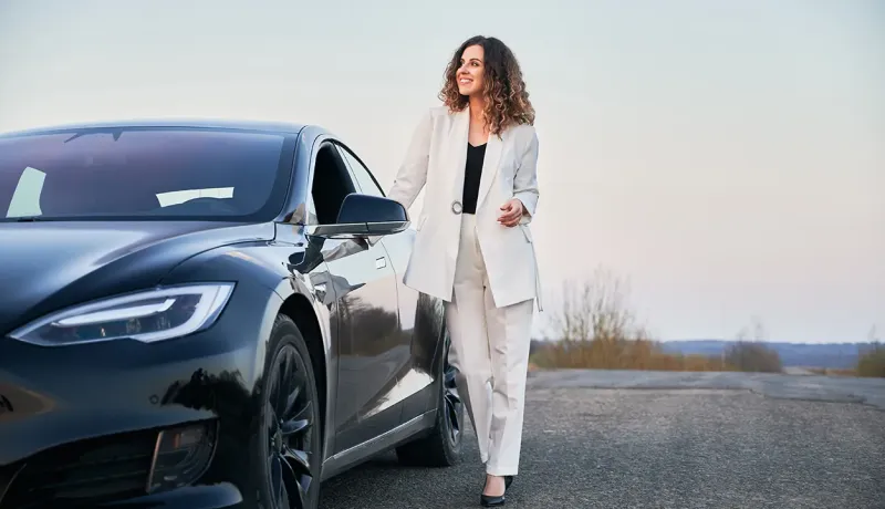 Femme en tenue professionnelle debout à côté de sa voiture